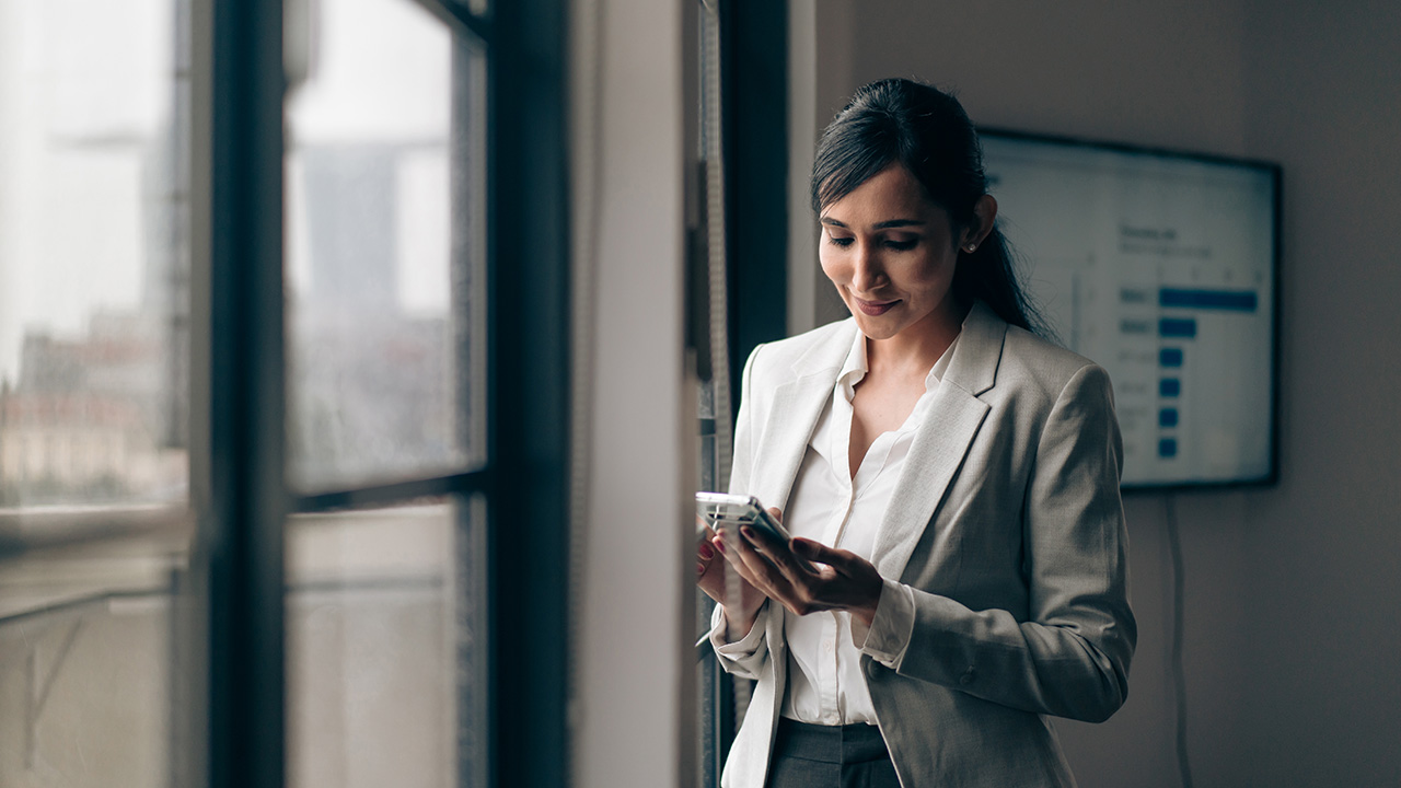 Young businesswoman reviewing her phone in an office, representing proactive tax planning