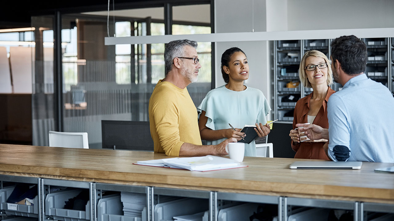 Business colleagues in conversation at a standing desk, representing a successful business exit